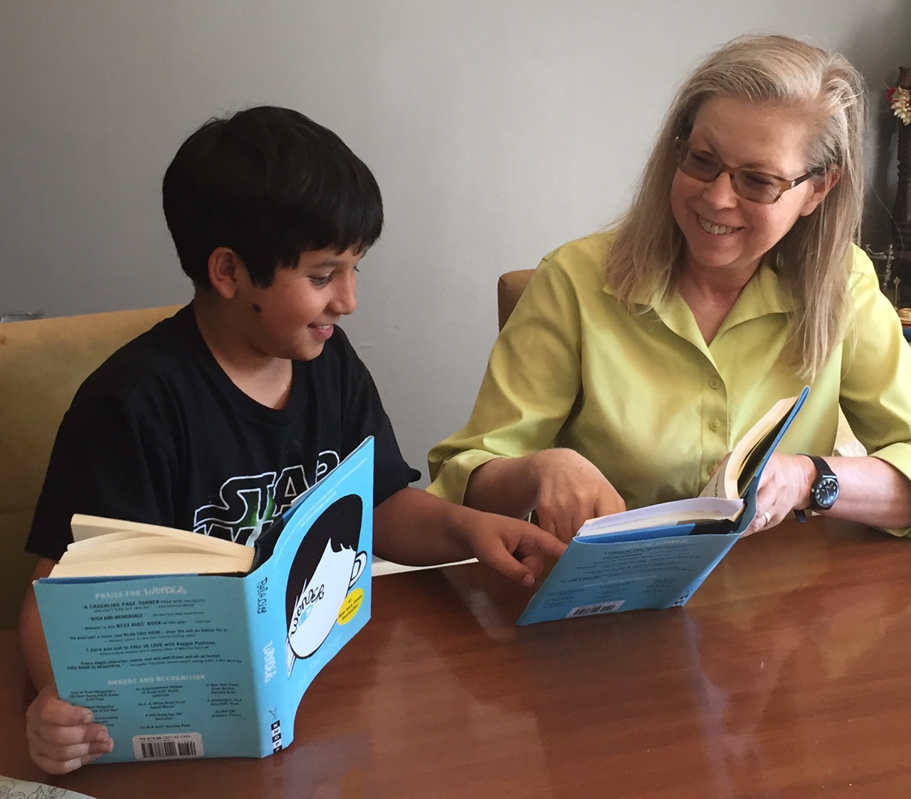 Kim teaching English to a boy, both holding a book.