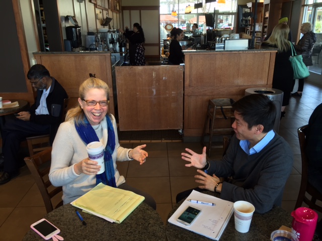 Kim talking with a man in a café.